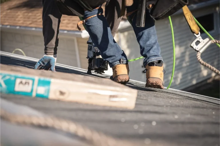 "Roofing contractors working on a residential asphalt roof installation, wearing safety gear and using tools.