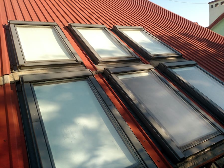 Red tiled house roof with attic windows. Roofing construction, window installation, modern architecture concept.