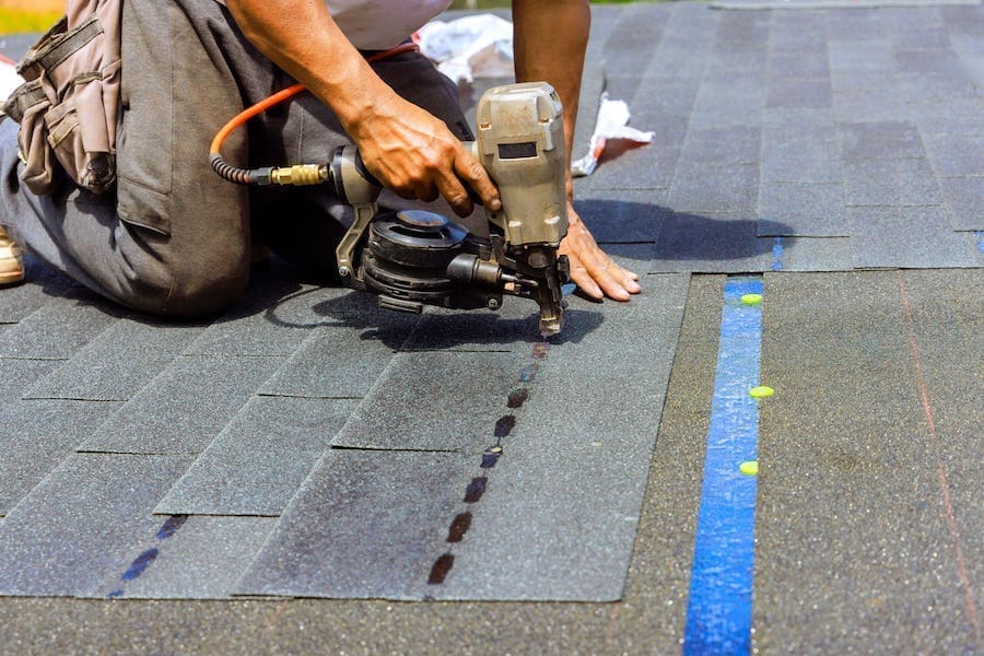 Professional roofer inspecting asphalt shingle roof in Wisconsin