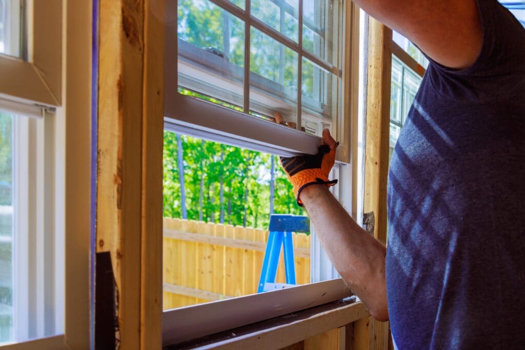 A window installation contractor replacing an old window with a new one.